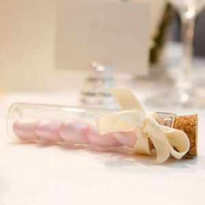 Reagenzglas mit Hochzeitsmandeln und rose Satinband