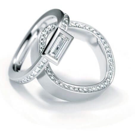Forma<br>Nicht rund, nicht eckig, die Fingerform besticht durch seine individuelle Formensprache und seinen großen Tragekomfort. Eine Diamant-Princess Reihe in aufregender Fassweise betont die außergewöhnliche Ringform.