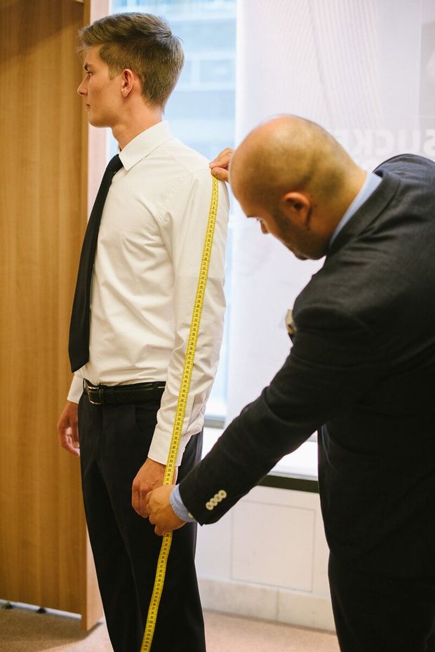 Ein Schneider nimmt an einem Mann Maß für einen neuen Anzug
