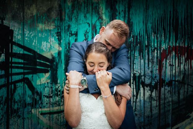 Braut und Bräutigam in Umarmung vor farbiger Wand - wilde Herzen Fotografie